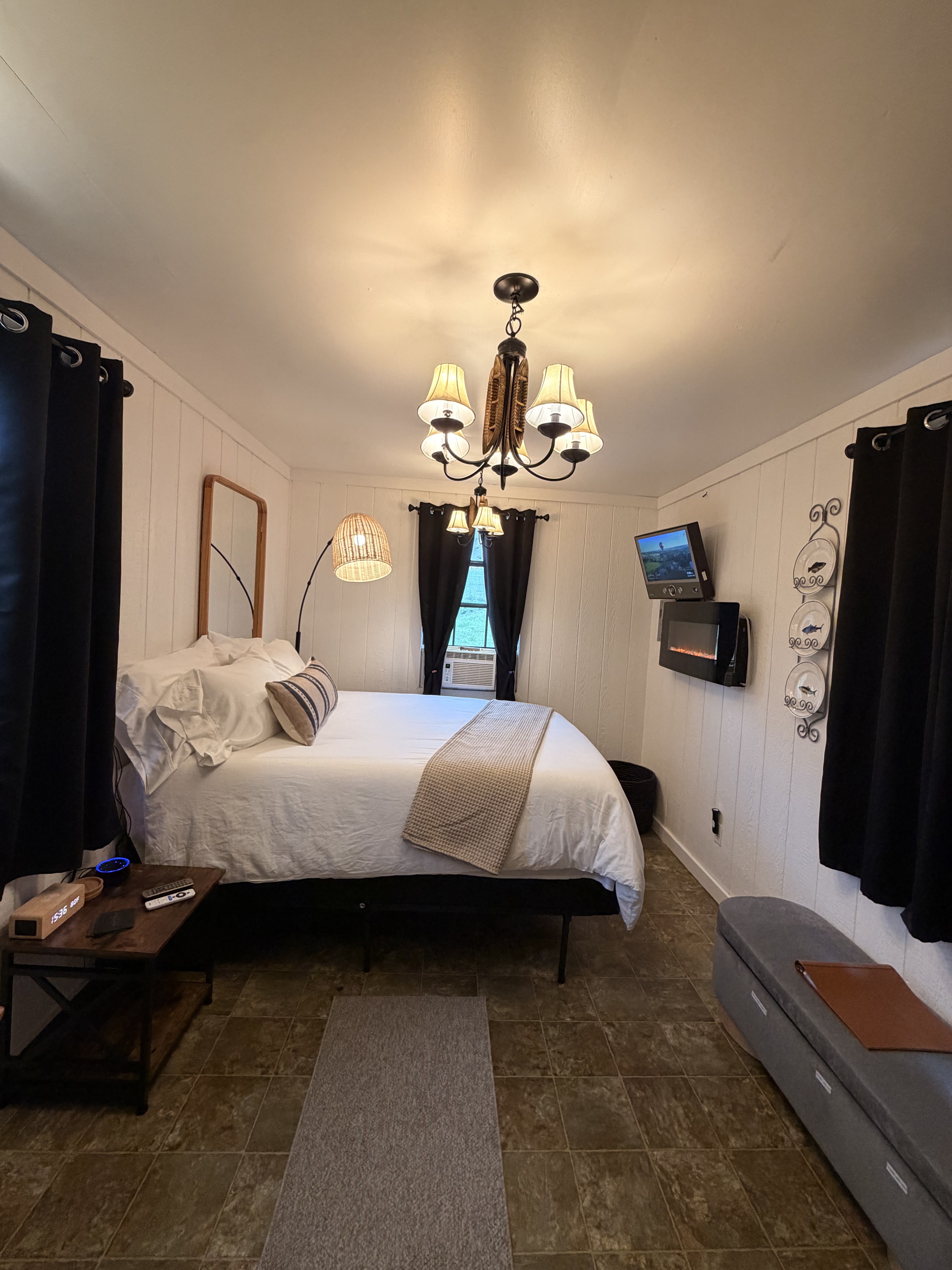Cozy bedroom with plush bedding, warm lighting, TV, and A/C